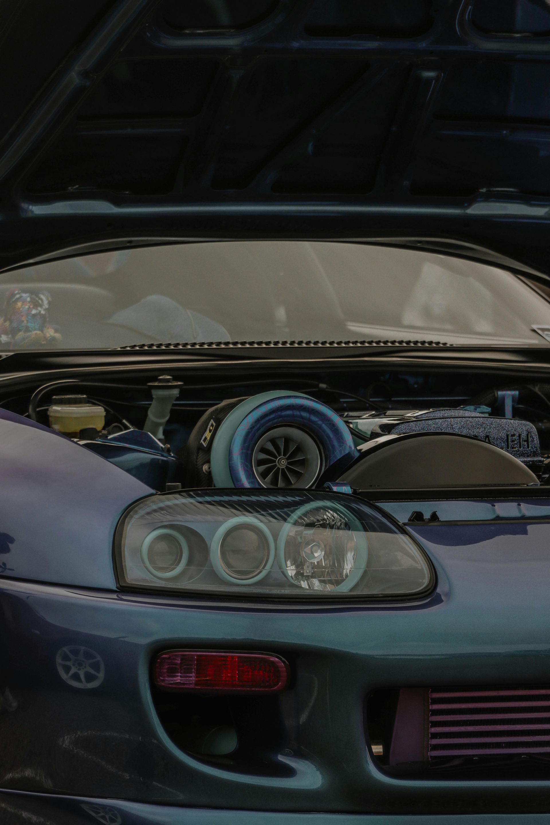 Blue Toyota Supra with the hood open, showcasing a large turbocharger.
