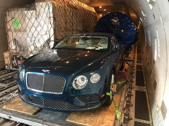 een blauwe bentley zit achterin een vliegtuig.