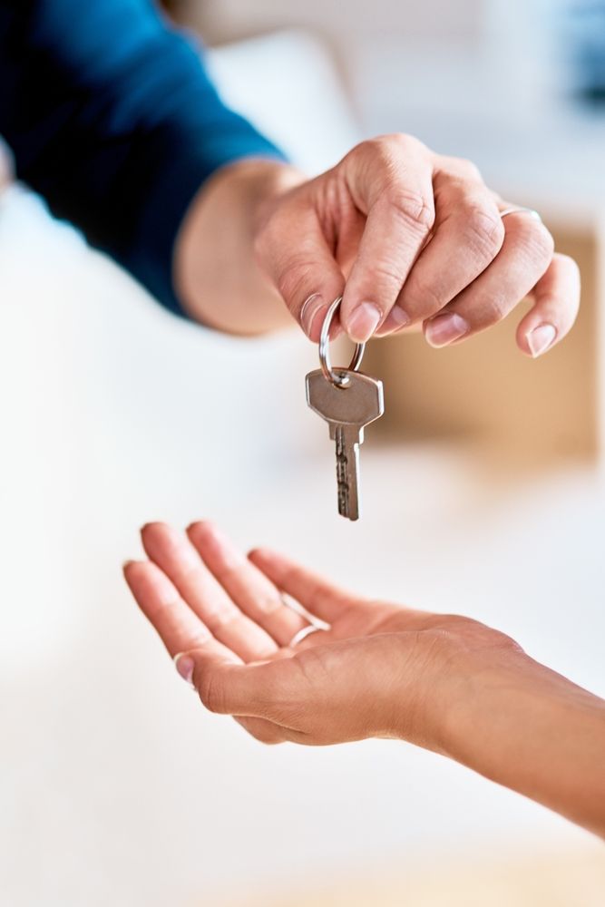 A hand holding a key and handing it to another open, outstretched hand. — Diamond Real Estate QLD in North Lakes, QLD