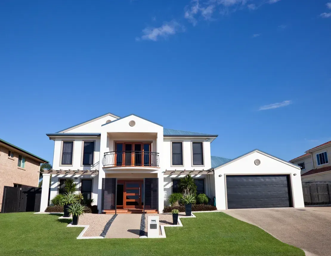White Two-story House With a Black Garage Door and Green Lawn Under a Blue Sky — Diamond Real Estate QLD in North Lakes, QLD