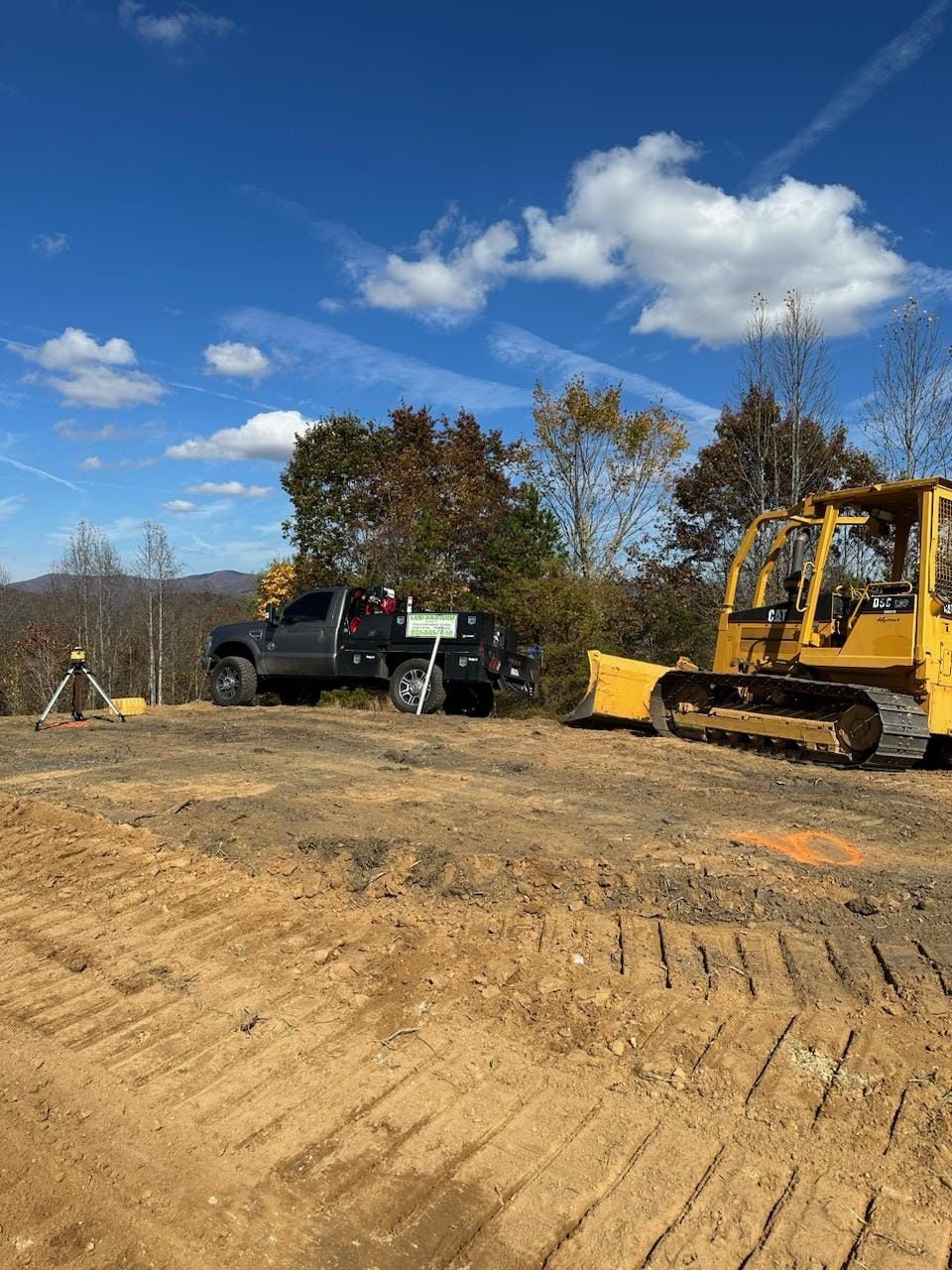 A bulldozer and a truck are in a dirt field - Alexander, NC - Land Solutions, LLC