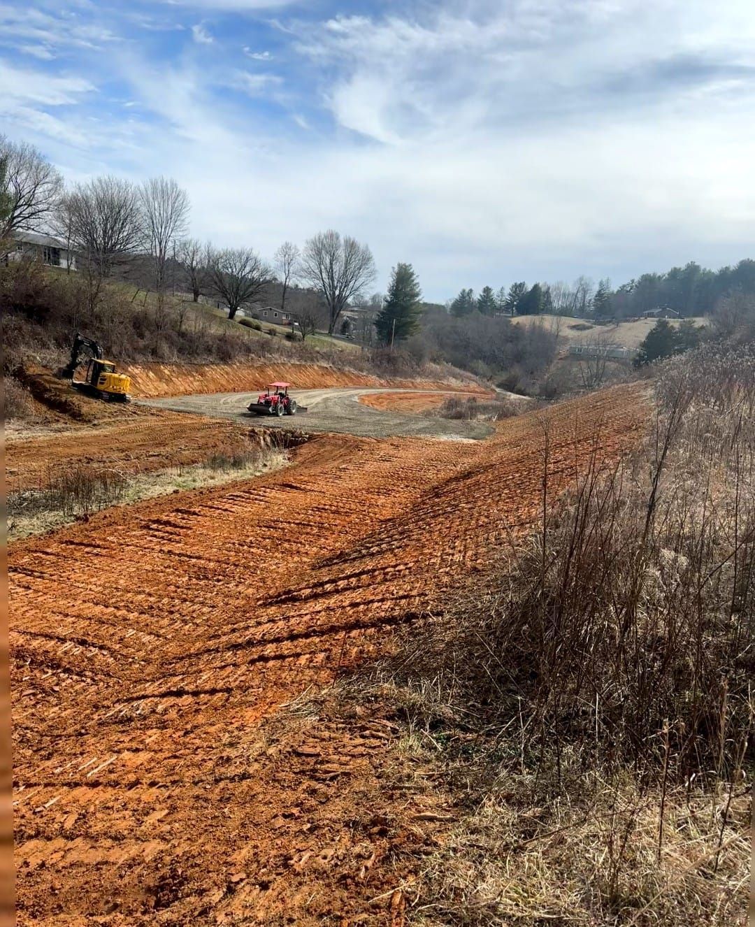 A dirt road in the middle of a field with a bulldozer in the background - Alexander, NC - Land Solutions, LLC