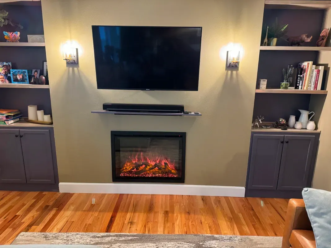 Living room with fireplace, TV, and built-in shelves in a neutral setting.