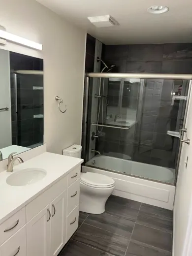 Bathroom with white vanity, toilet, dark countertop, gray walls, and dark tiled floor.
