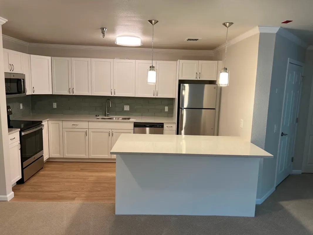 White kitchen with stainless steel appliances, white cabinets, and a breakfast bar.