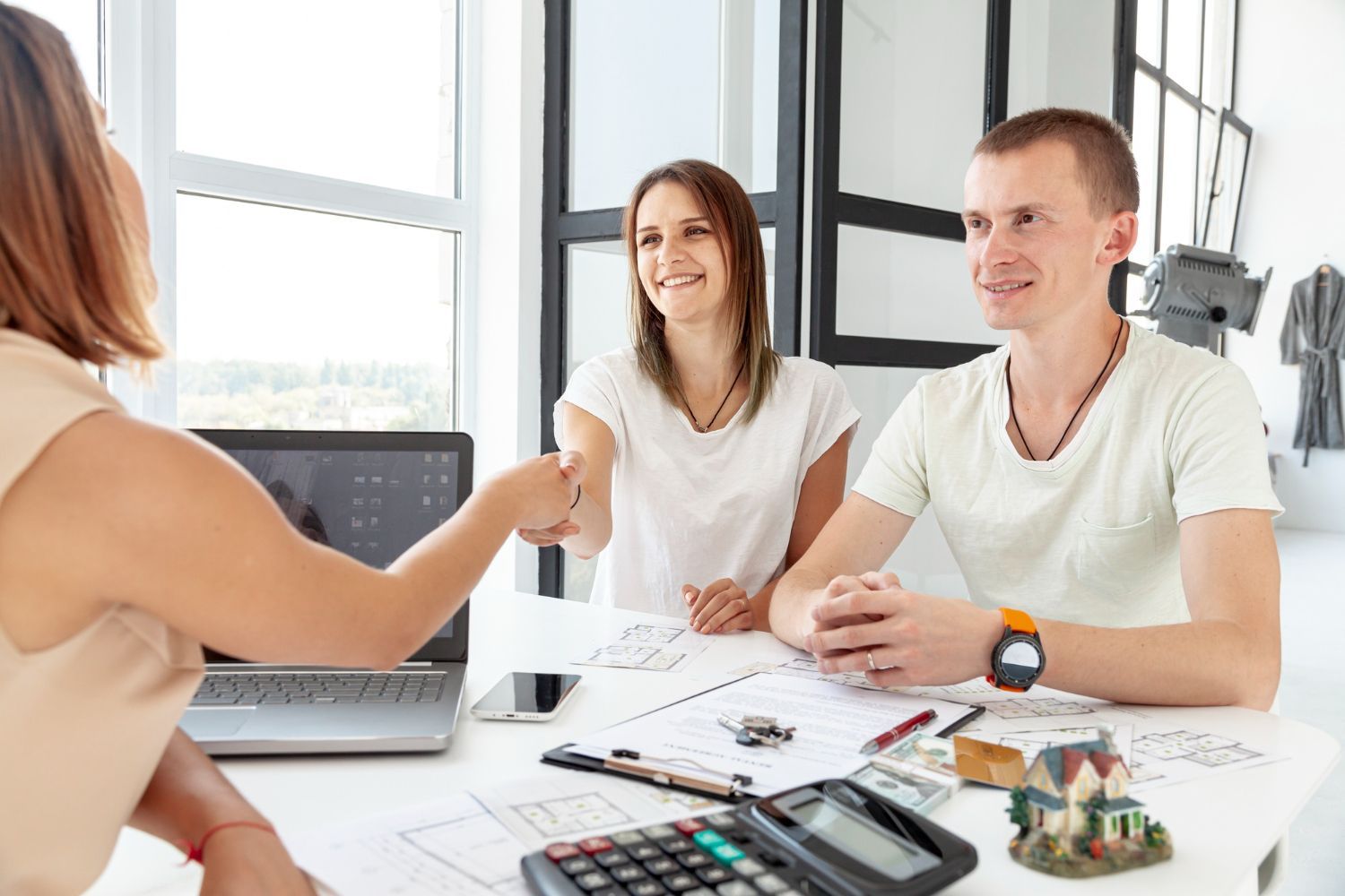 A man and a woman are shaking hands while sitting at a table.