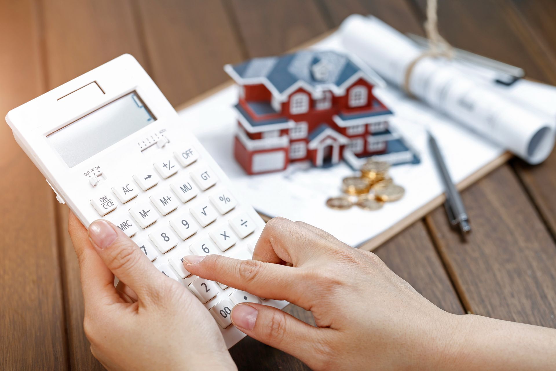 A person is using a calculator to calculate the cost of a house.