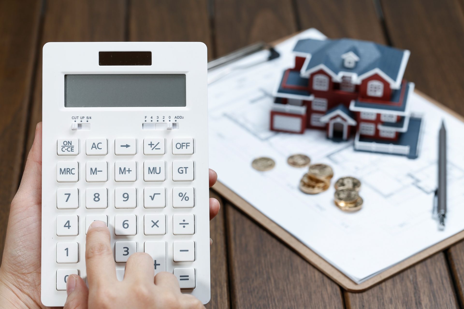 A person is using a calculator to calculate the cost of a house.