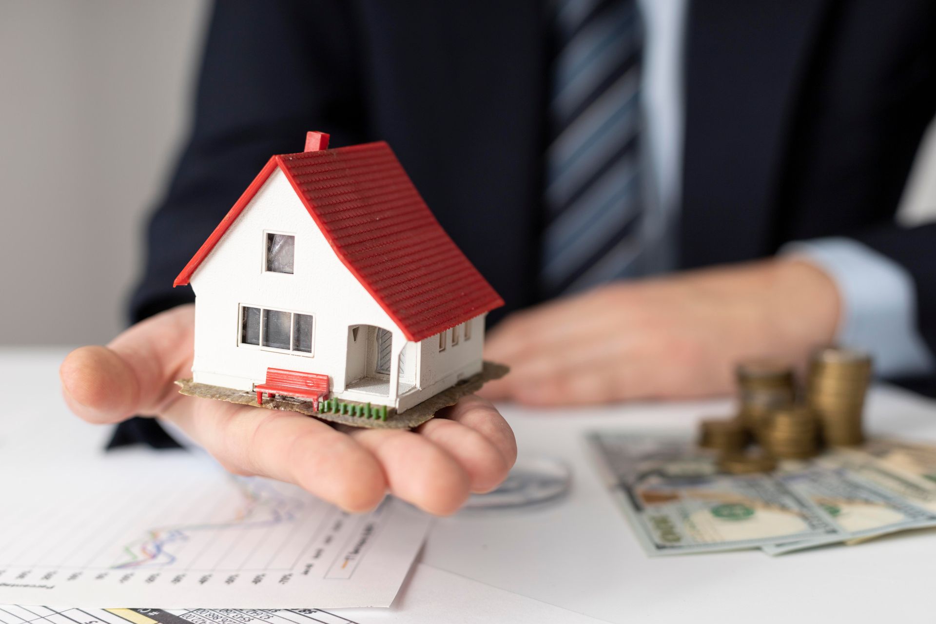 A man is holding a small model house in his hands.