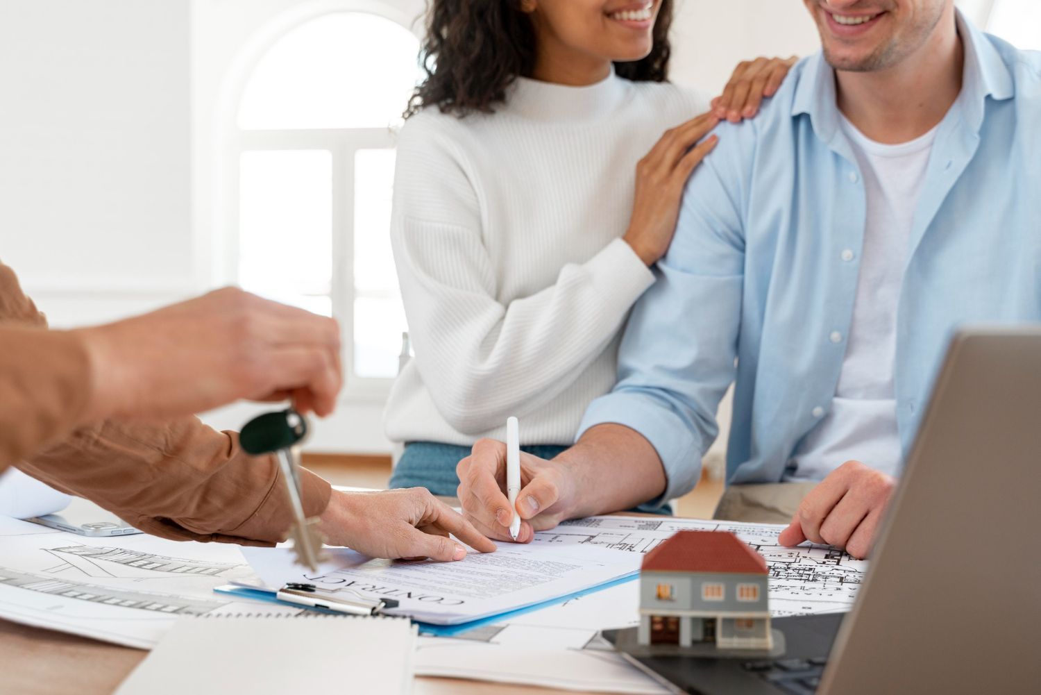 A man is giving a key to a woman while they sign a document.
