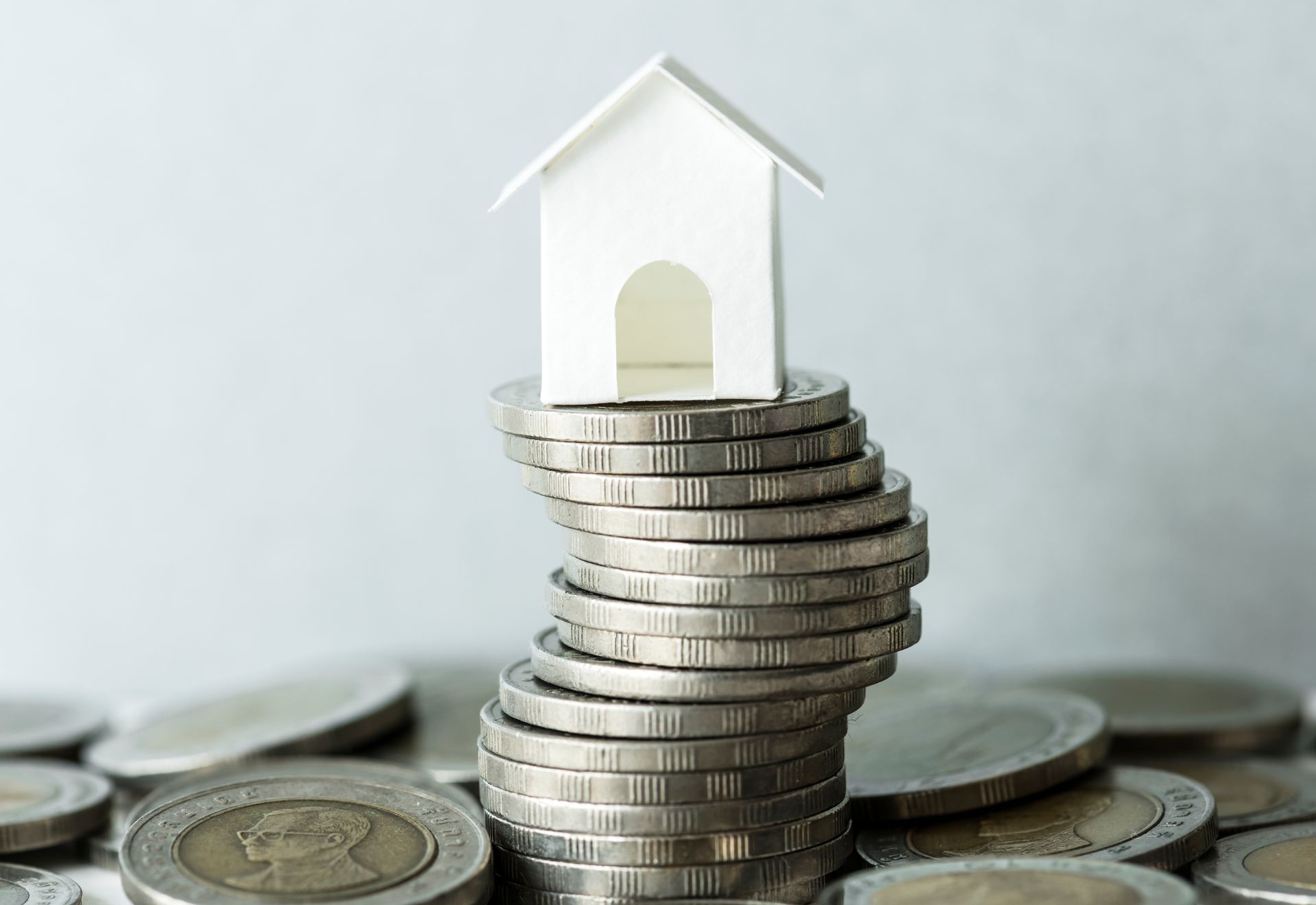 A model house is sitting on top of a pile of coins.