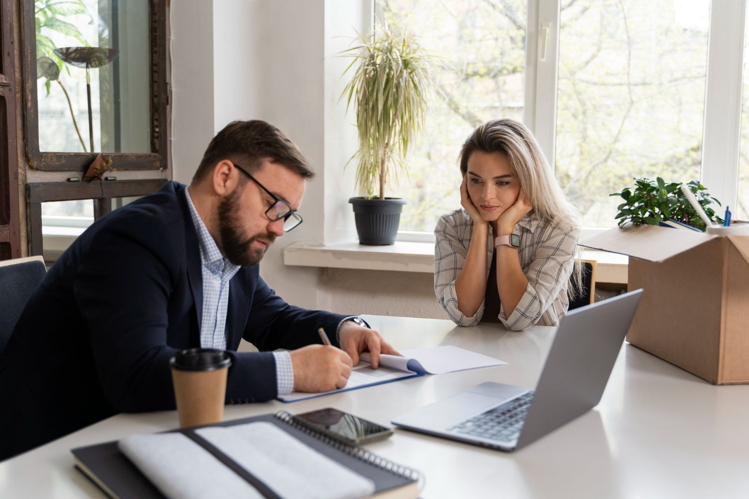 A man and a woman are sitting at a table with a laptop.