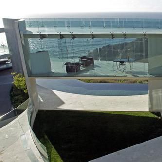 A view of the ocean from the balcony of a modern house.