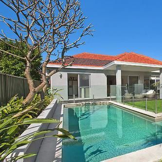 A house with a large swimming pool in front of it.