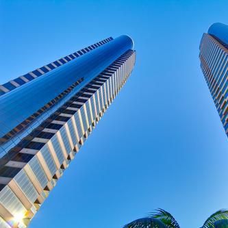 Looking up at two tall buildings against a blue sky