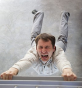A man is laying on his back with his mouth open while holding onto a railing.