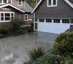 A brown house with a white garage door and a concrete driveway.