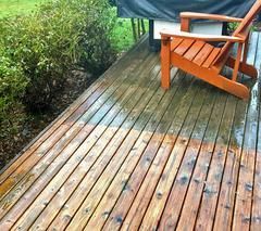 A wooden deck with a chair on it is being cleaned.