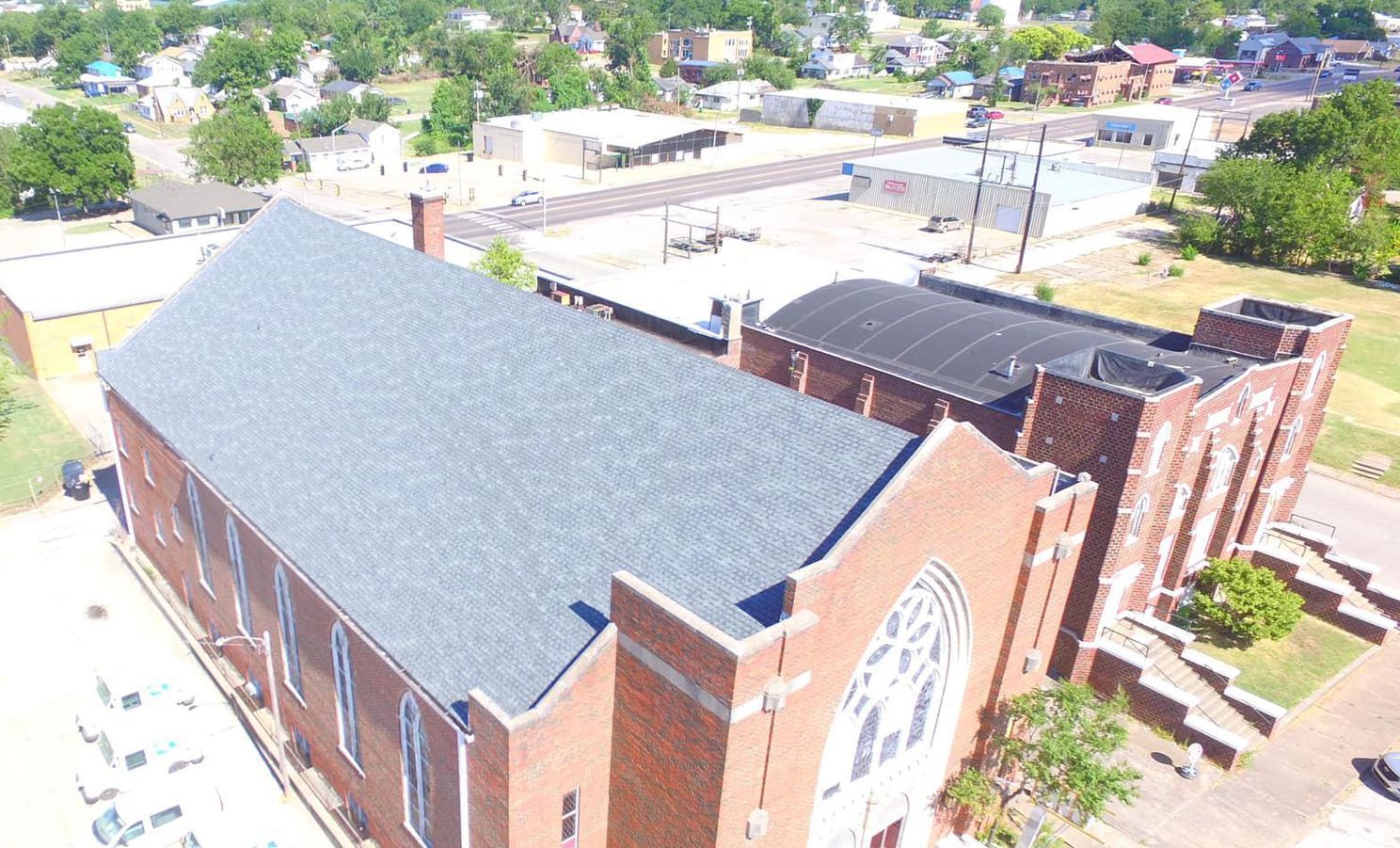 An aerial view of a large brick church in a small town