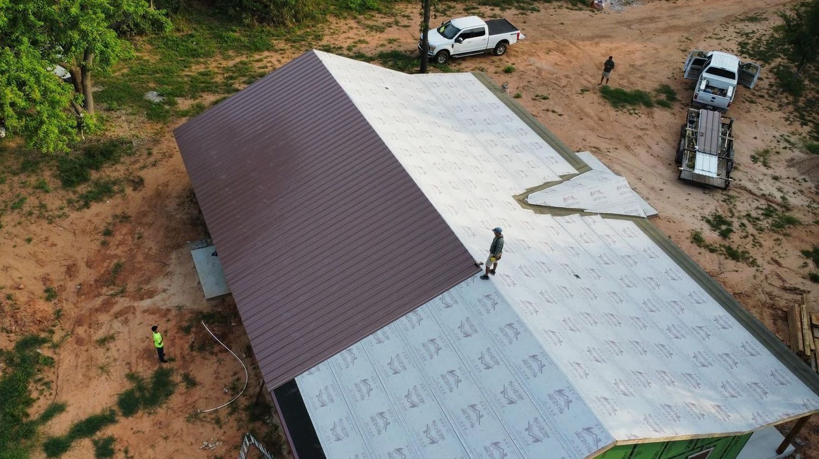 An aerial view of a building under construction with a roof being installed.