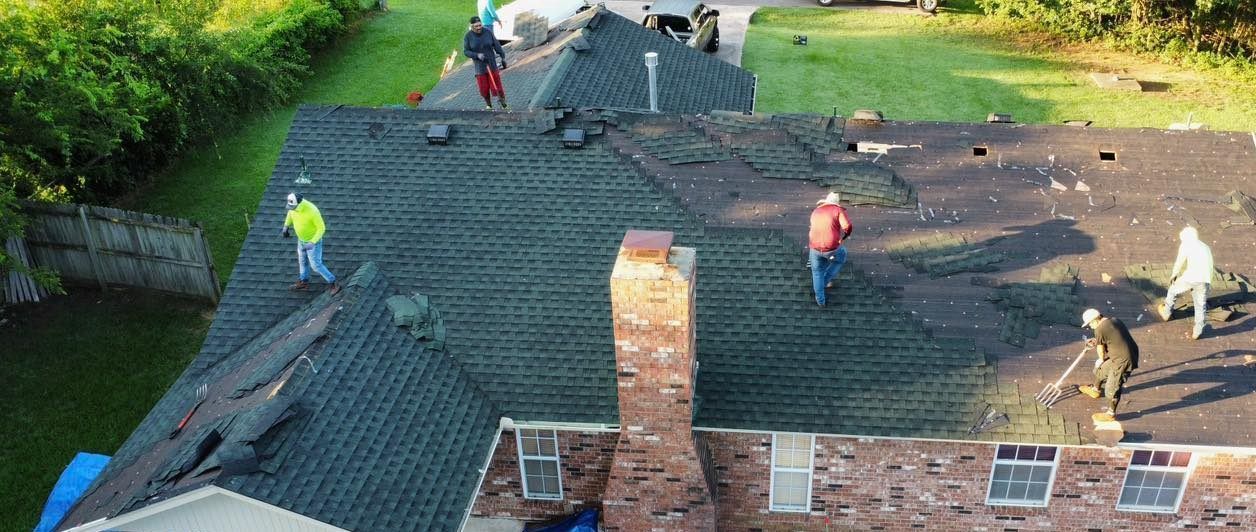 A group of people are working on the roof of a house.