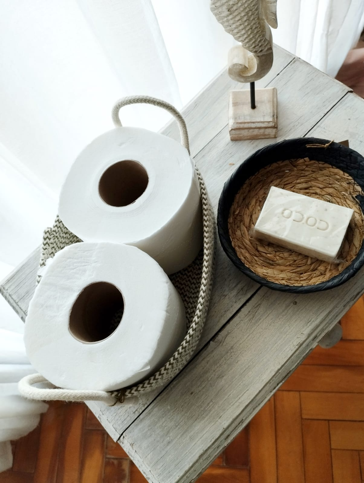 Dos portarrollos de papel higiénico tejidos sobre una mesa rústica
