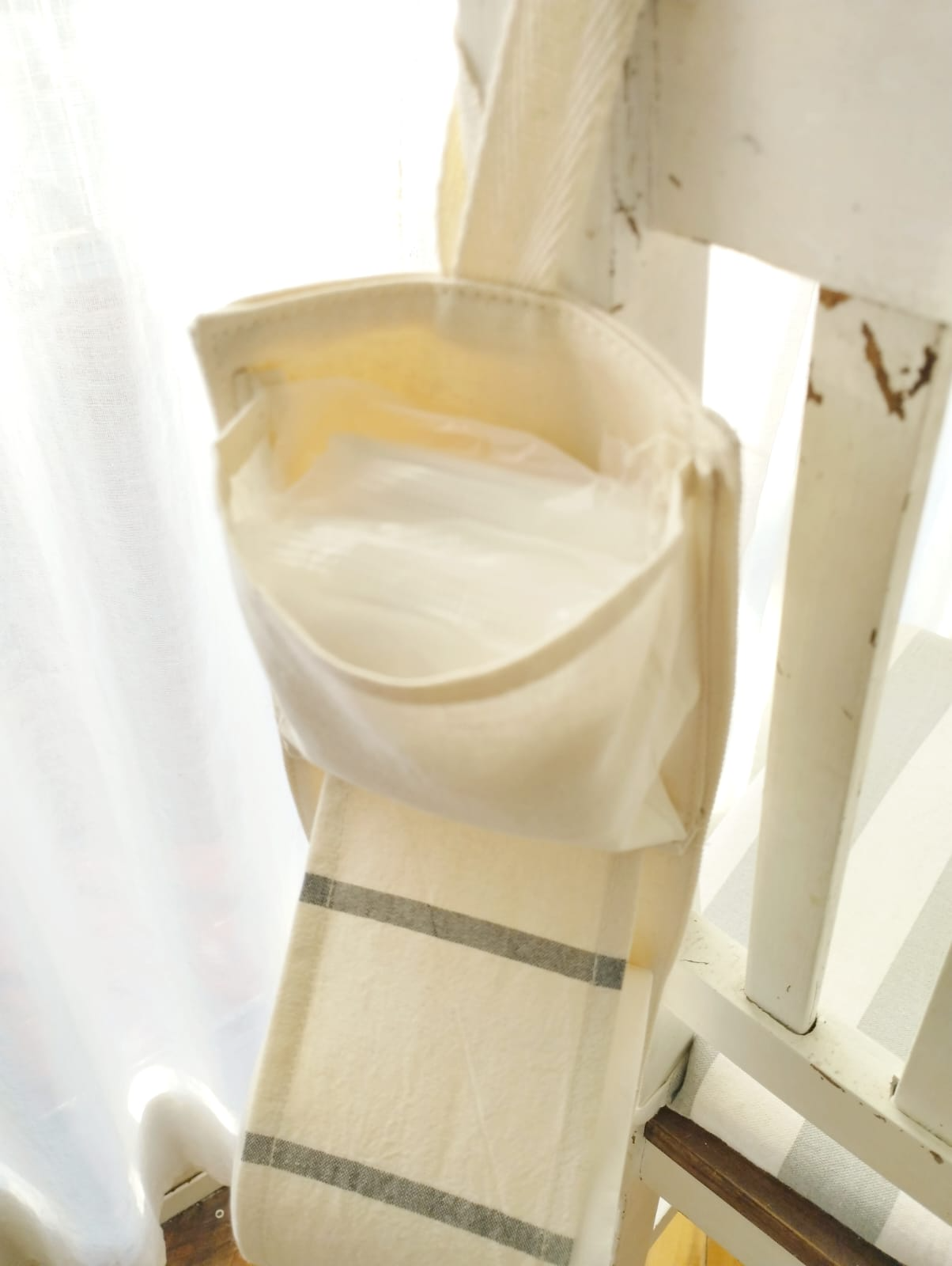 Rollos de papel higiénico beige apilados colgando de un sujetador de cortina.