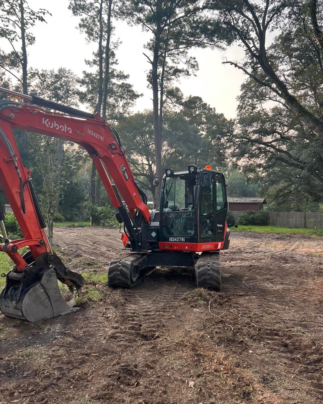 A red and black excavator is sitting on top of a dirt field.