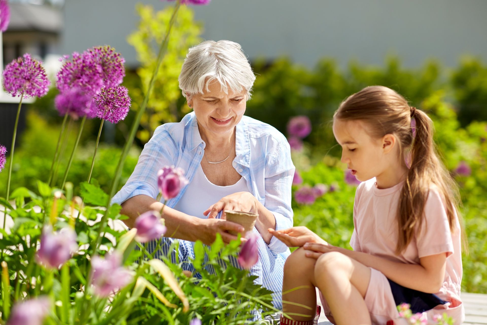 Grandmother and granddaughter planting seeds in the garden.