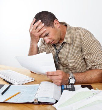 a man is sitting at a desk looking at a piece of paper