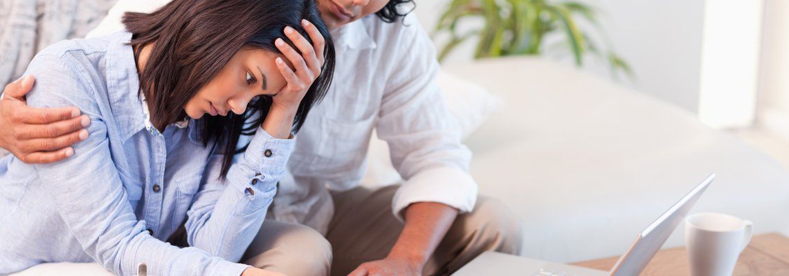 a man comforts a woman who is looking at a laptop