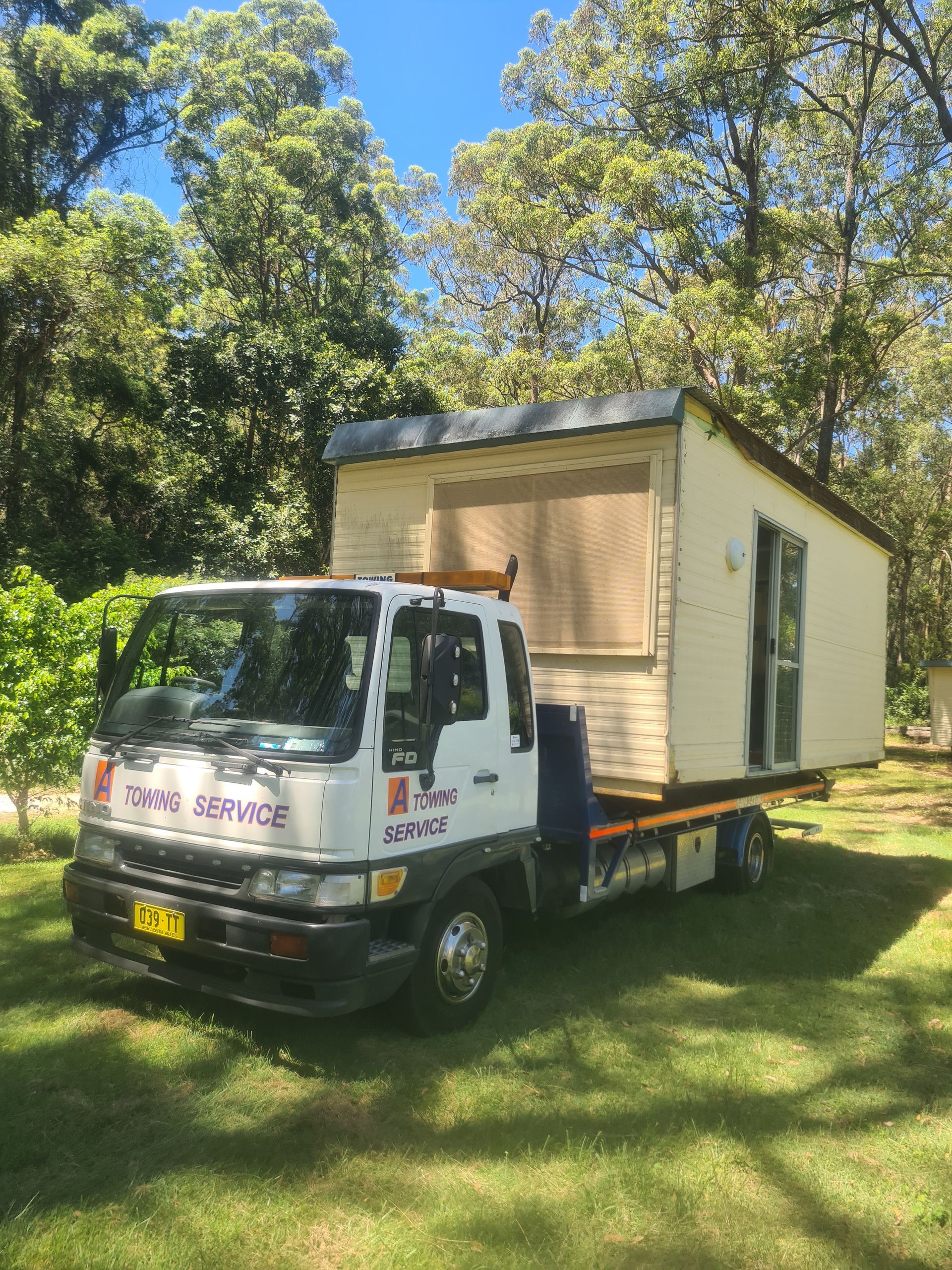 A truck is carrying a small house on the back of it. — A Towing Service In Forster, NSW