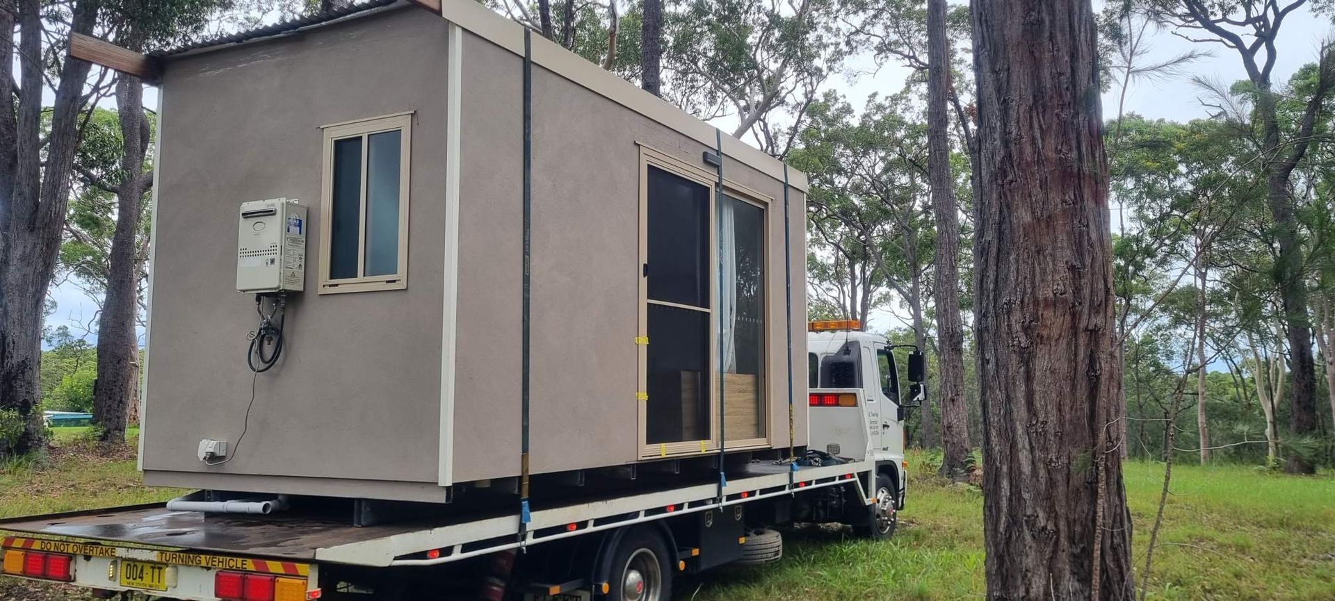 Small Gray Cabin Being Transported on a Truck — A Towing Service In Smiths Lake, NSW