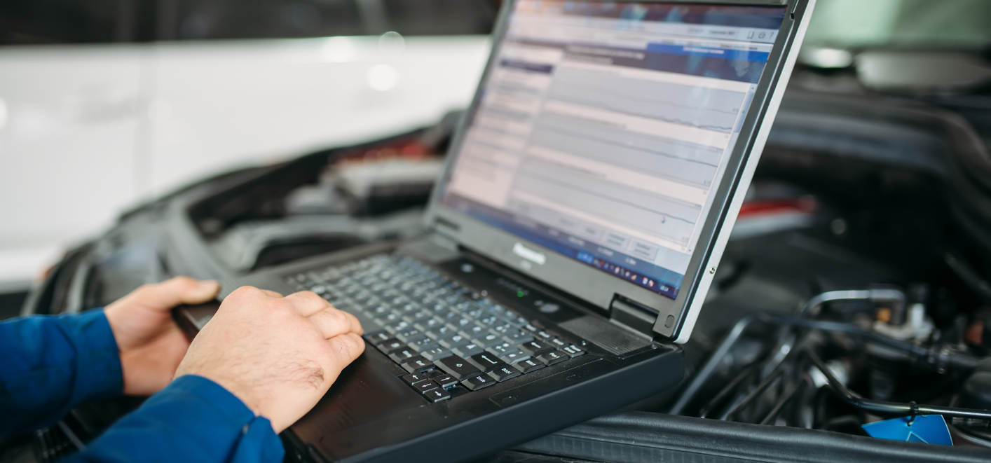 Mechanic doing diagnostic work on a vehicle using a computer.