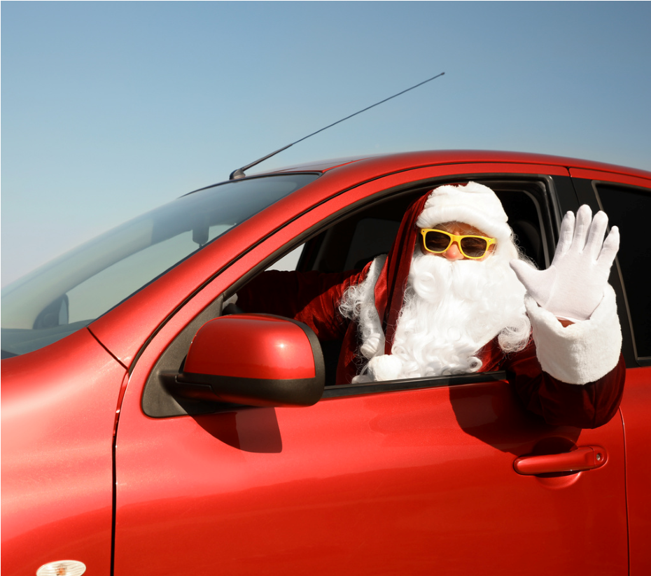Santa Claus in red car, waving, wearing sunglasses.