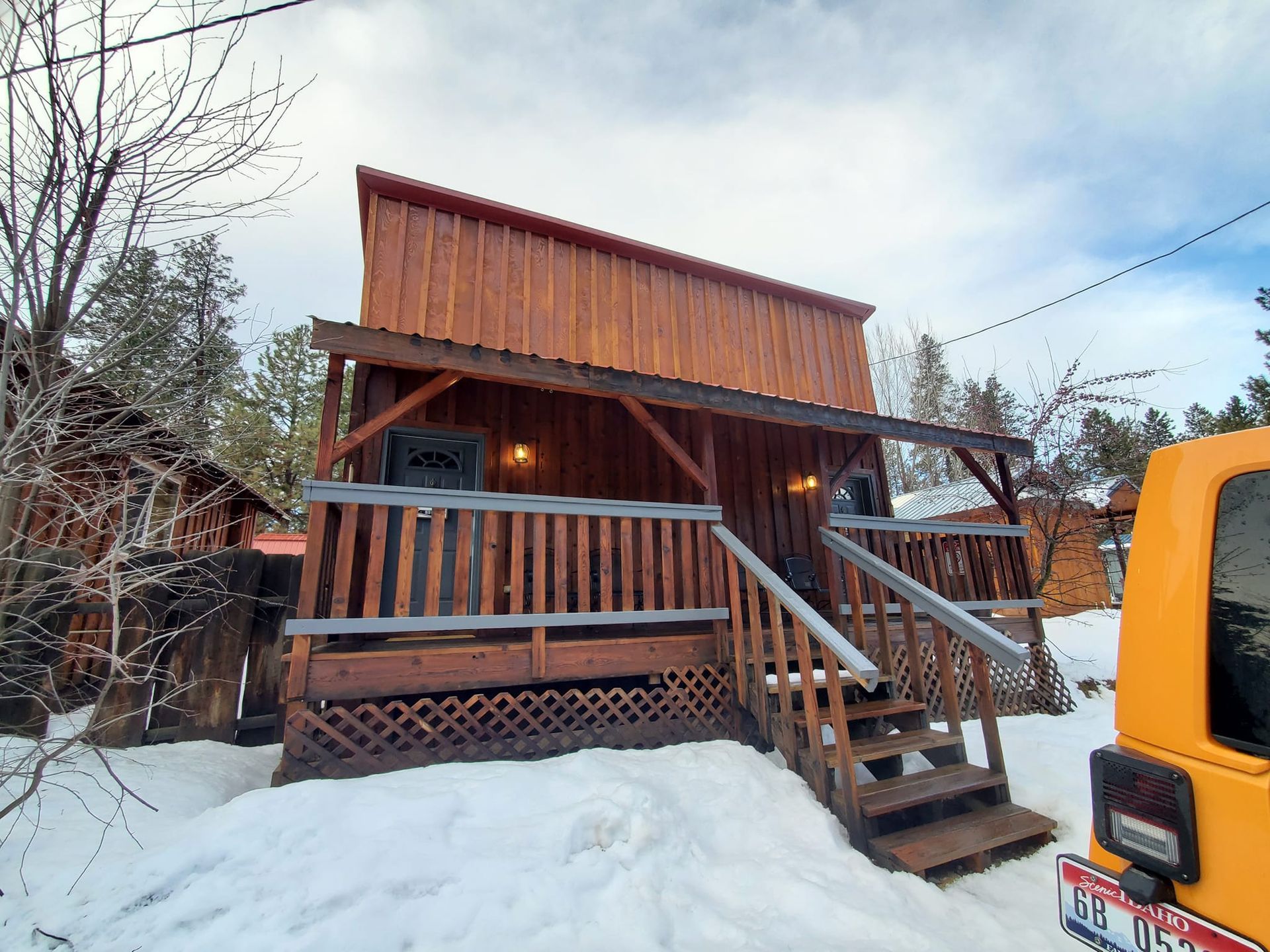 A yellow school bus is parked in front of a wooden cabin in the snow.