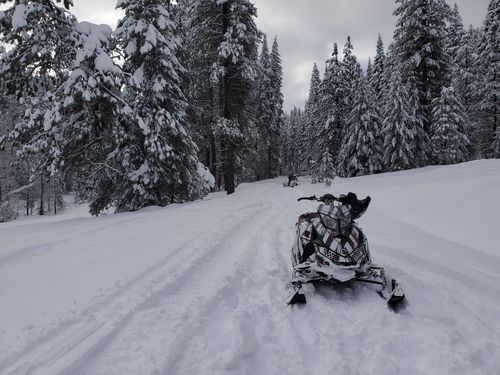 A snowmobile is driving down a snow covered road