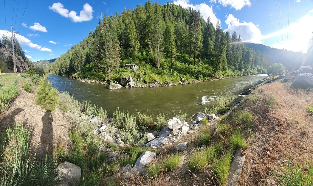 A panoramic view of a river surrounded by trees and rocks.