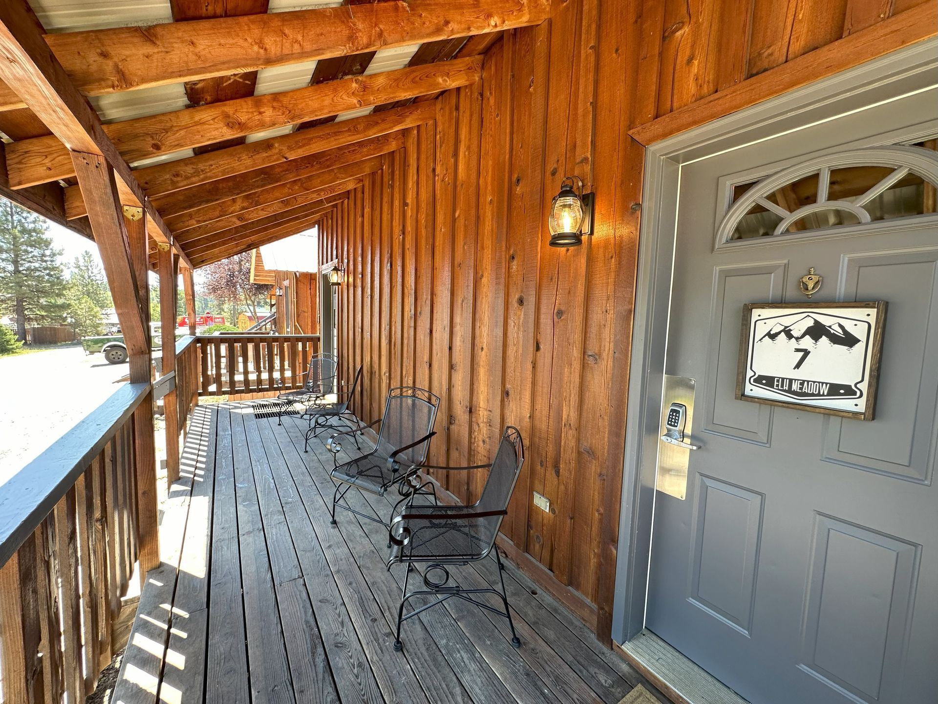 A wooden porch with chairs and a gray door.