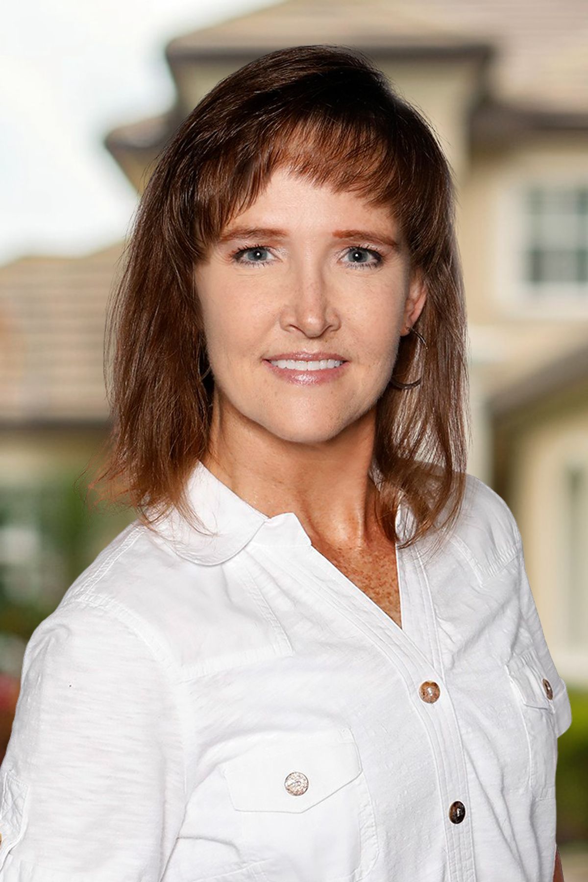 A woman is sitting at a desk with a laptop and a vase of flowers.
