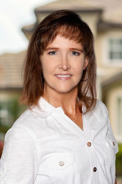 A woman is sitting at a desk with a laptop and a vase of flowers.