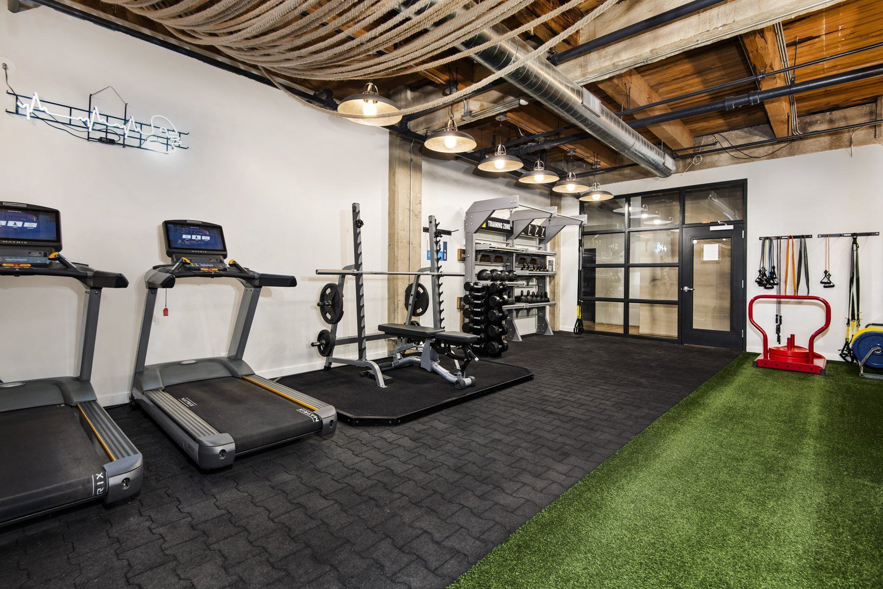 a gym with treadmills and other exercise equipment on a green rug