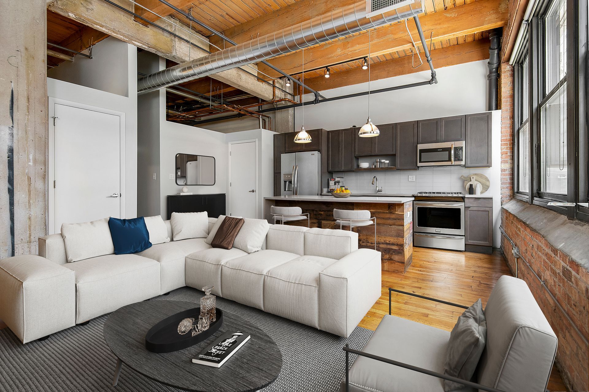 A living room with a white sectional couch , chairs , and a coffee table at The Lofts at Gin Alley.