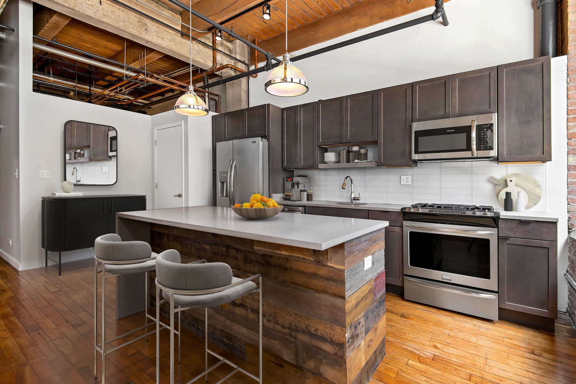 A kitchen with stainless steel appliances and wooden cabinets at The Lofts at Gin Alley.