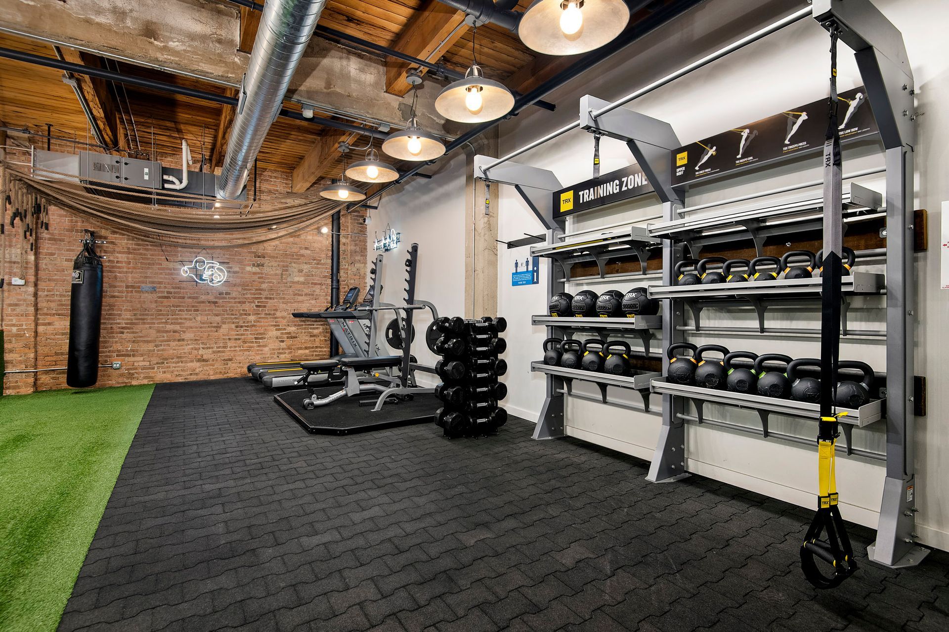 A gym with a lot of equipment and a brick wall at The Lofts at Gin Alley.