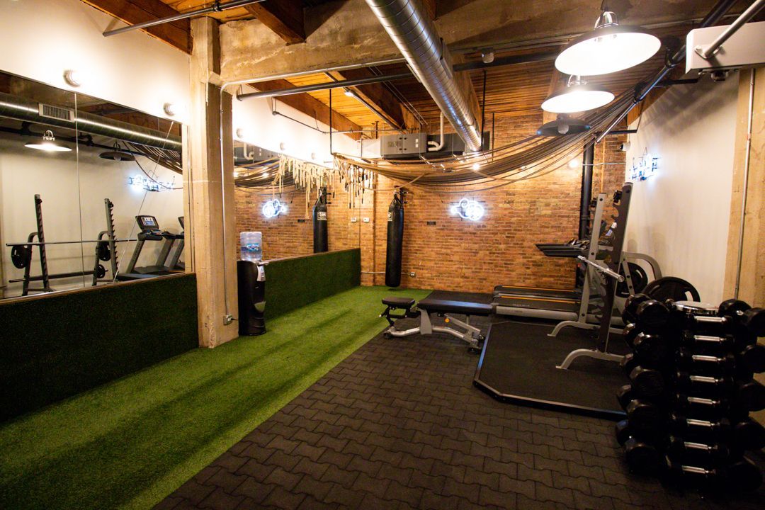 A gym with a treadmill , dumbbells , and a bench at The Lofts at Gin Alley.
