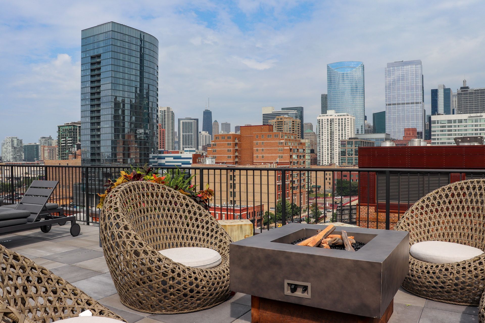 A patio with wicker chairs and a fire pit with a city skyline in the background at The Lofts at Gin Alley.
