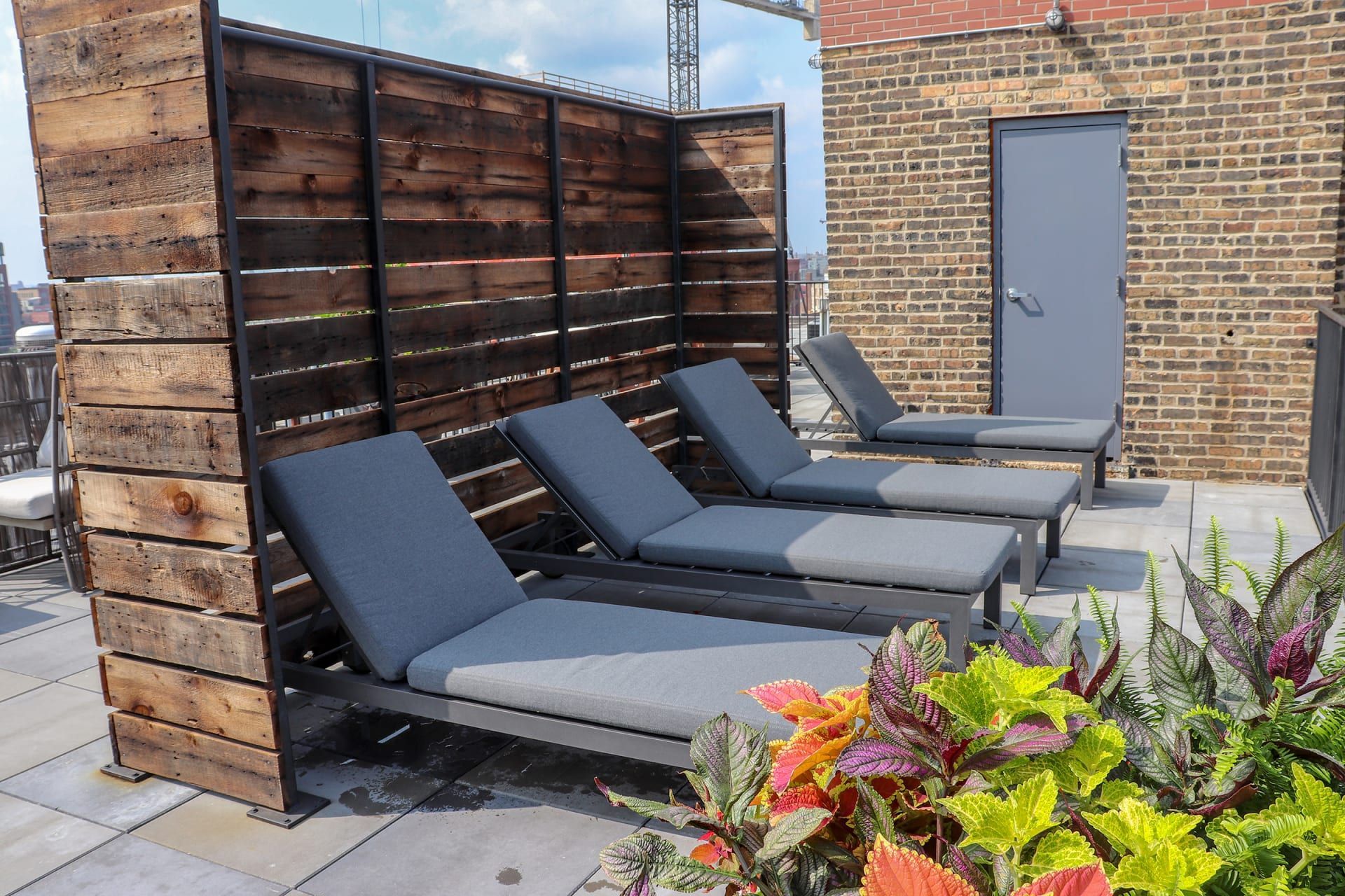 a row of blue lounge chairs on a patio with a brick building