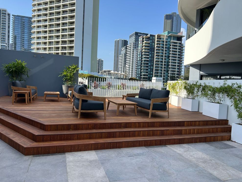 Outdoor seating area on a wooden deck with modern furniture against a city skyline. Resort Renovation.