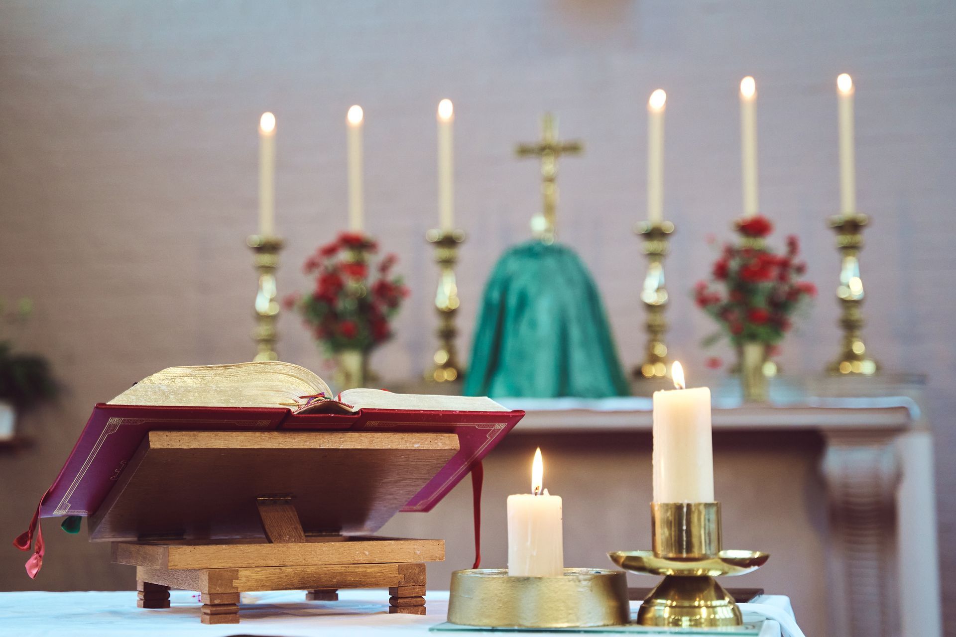 A bible and candles are on an altar in a church.